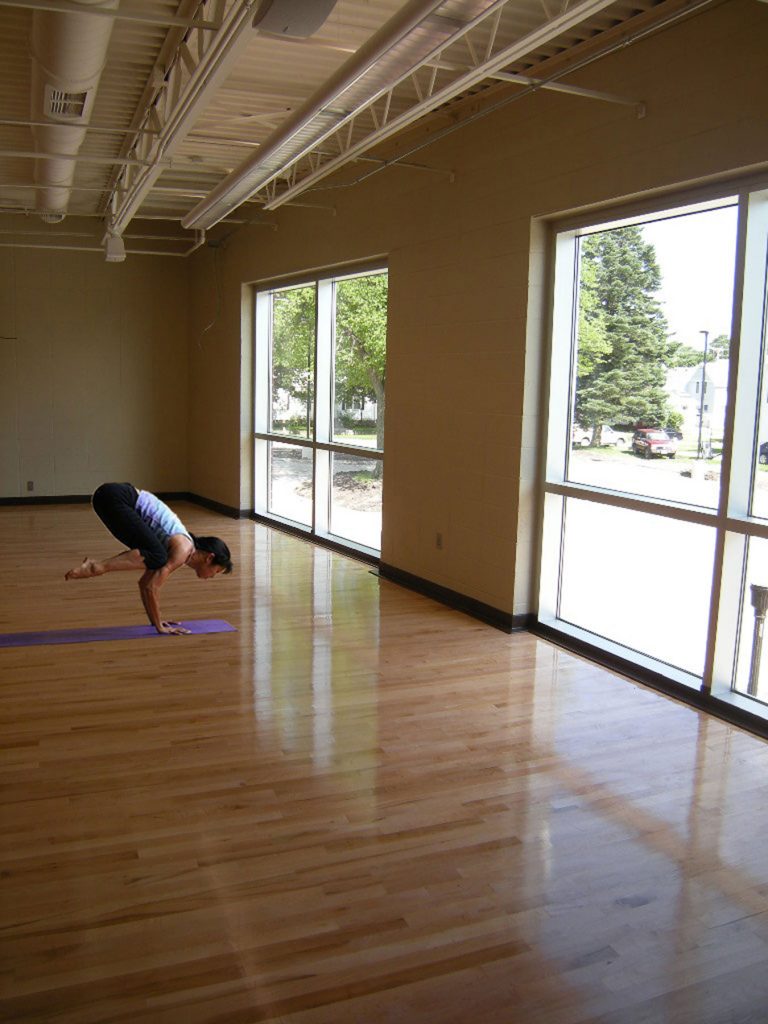 Woman practicing yoga on a purple mat in front of windows