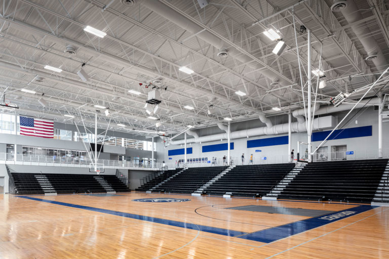 Gymnasium with bleachers deployed and students walking the track above