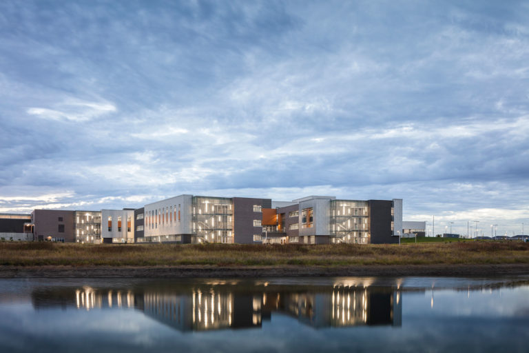 Exterior of building at dusk with reflection in water