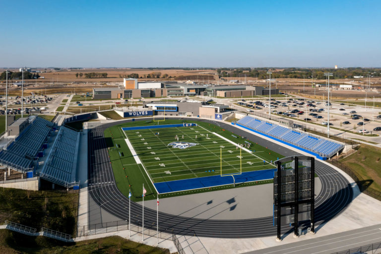 Aerial view of football field looking toward team building and high school