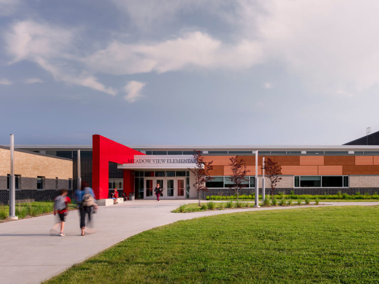 Exterior photo of building entry with red and wood toned metal panels