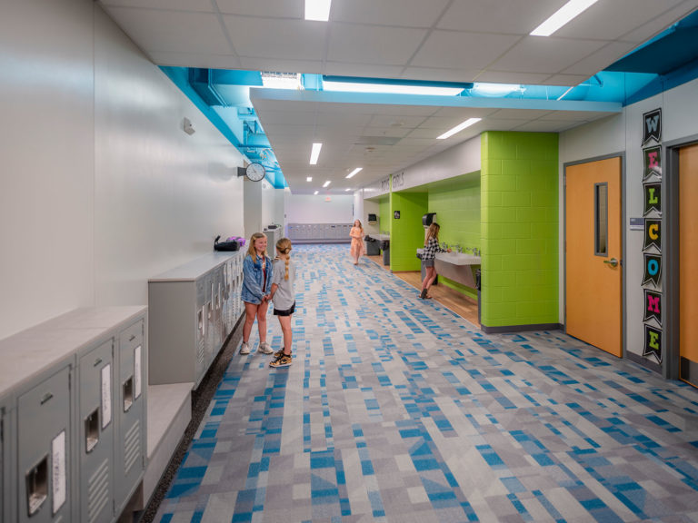 Classroom wing corridor with painted ceiling reveals and colored carpet